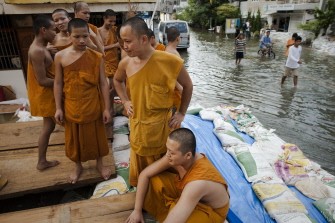 Buddhist monks construct a sand bag wall to block flood waters from entering their temple, in a street near the Chao Praya river in Bangkok on October 26, 2011.