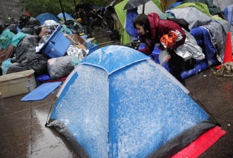 AFP - A medical volounteer supporting Occupy Wall Street check tents to see if fellow supporters are in need of medical help as the first snow falls over Zuccotti Park in New York, October 29, 2011.