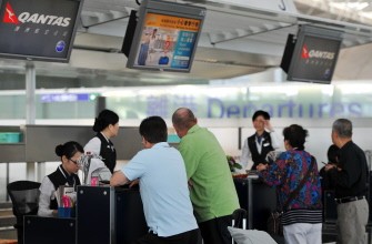 Travellers listen to a ground staff (3rd-R) at a Qantas counter at Hong Kong International Airport on October 31, 2011.