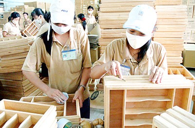 Workers produce wood furniture at a company. (Photo: SGGP)