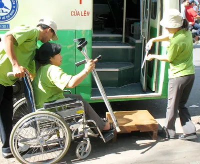Giúp đỡ người khuyết tật lên xe buýt. Ảnh: C.T.V.