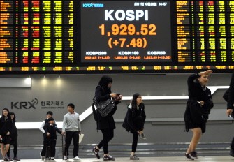 High school students walk past a stock index board as they visit the Korea Stock Exchange in Seoul on October 28, 2011.