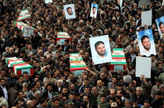 Mourners carry coffins and pictures of killed Major General Hassan Moqaddam during the funeral of members of Iran's elite Revolutionary Guards in Tehran on November 14, 2011.