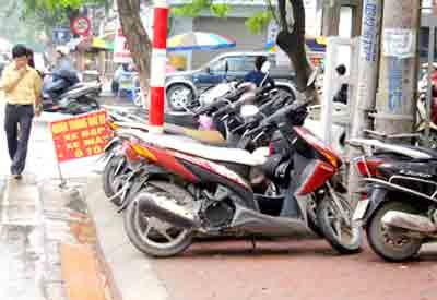 A parking lot occupies an entire pavement, pushing vendors onto the main road (Photo: Sai Gon Giai Phong)