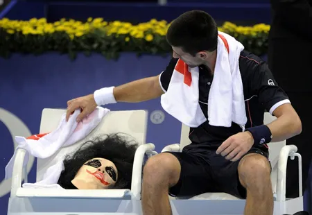 Djokovic đang “chăm sóc” chiếc mặt nạ trong thời gian nghỉ giữa trận đấu với Malisse.