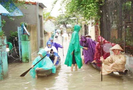 Người dân thành phố Huế phải dùng thuyền nhỏ để di chuyển trên đường nhựa bị ngập lụt. Ảnh: Văn Thắng