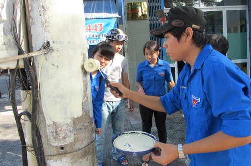 (Da Nang newspaper file photo) Young volunteers in Da Nang erase illegal advertisements on an electricity pole in the city