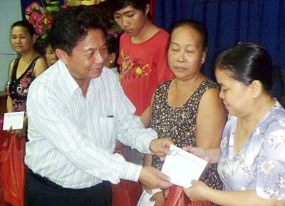 Tran The Tuyen (L), Editor-in-chief of SGGP Newspaper, hands over Tet gifts to disadvantaged people in Go Vap District. (Photo: Sggp)