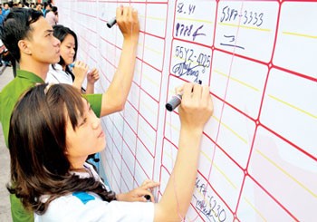 Young people in HCMC sign and registered their motorbike numbers pledging commitment to the no-violating road traffic law. (Photo: Sggp)
