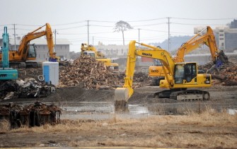 Heavy machinery removes the remnents of tsunami devastation in Rikuzentakata city, Iwate prefectura on March 8, 2012 as a 10-metre-high pine tree stands in the background after surviving the March 11 tsunami. (AFP Photo)