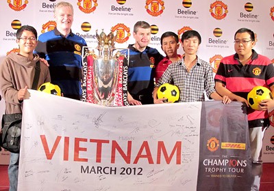 Gordon McQueen and Denis Irwin pose with Vietnamese fans alongside the Premier League Cup