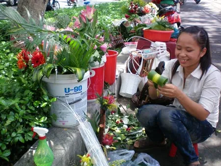 Huyền Trang - tình nguyện viên quỹ từ thiện "Nếp sống đạo" đang cắm hoa tươi bán tại đường Nguyễn Văn Cừ (quận 5, TPHCM). Huyền Trang cho biết, mọi năm số tiền thu được từ công việc bán hoa tươi cho khách khoảng 1-2 triệu đồng. Tuy nhiên, năm nay giá hoa các loại tăng hơn so với cùng kỳ năm 2011 nên đã ảnh hưởng phần nào đến sức mua. Hiện hoa hồng Đà Lạt mua tại chợ Hồ Thị Kỷ (quận 10) dao động từ 200.000-300.000 đồng/bó 50 bông.