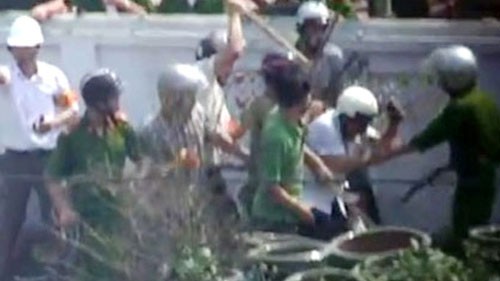 Journalist Nam (wearing helmet in whiter shirt) is beaten by some men wearing police uniforms with sticks ( photo VOV).