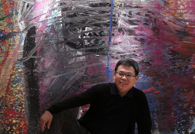 In this photo taken on Monday, April 2, 2012, Indonesian-Chinese farming tycoon Budi Tek poses in front of a painting by Gerhard Richter during an auction preview in Hong Kong.