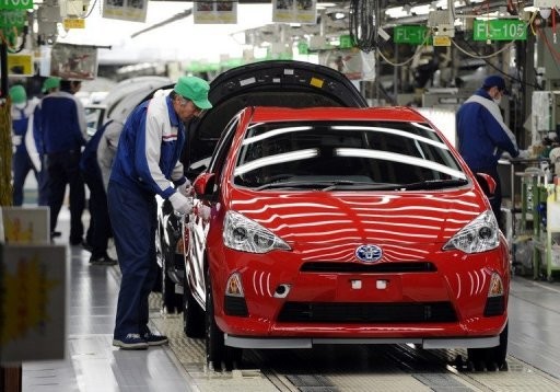 File photo shows workers making final checks on Toyota's compact hybrid vehicle AQUA on its assembly line in Tokyo.