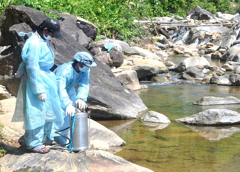 Medical workers take samples of water from a stream where residents of Ba Dien Commune draw water for daily use