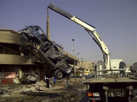 A burnt vehicle is removed from the site of a bomb attack, which killed Shi'ite pilgrims who were making their way to a religious festival, in Baghdad June 13, 2012.