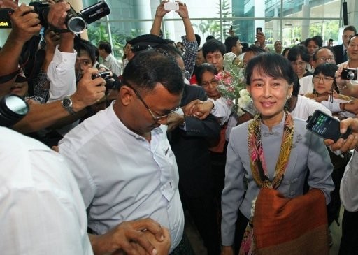 Myanmar opposition leader Aung San Suu Kyi (C) is surrounded by media representatives ahead of her departure at Yangon International Airport.