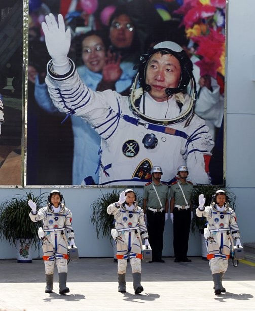 China's astronauts from left., Liu Yang, Jing Haipeng and Liu Wang wave and walk before a giant portrait of China's first astronaut Yang Liwei, as they depart for the Shenzhou 9 spacecraft rocket launch pad at the Jiuquan Satellite Launch Center in Jiuquan, China, Saturday, June 16, 2012.