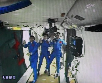 A photo of the giant screen at the Jiuquan space center shows three Chinese astronauts (from left) Liu Wang, Jing Haipeng and Liu Yang in the Tiangong-1 module on June 18, 2012.