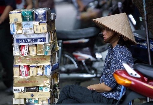 A cigarettes vendor is seen behind a pile of empty cartons of foreign and local cigarette brands, in Hanoi.