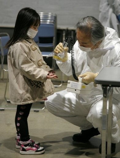 A little girl holds out her hands for a radiation scan at a screening center in Koriyama in Fukushima prefecture on March 22, 2011.