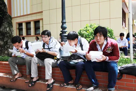 Một số thí sinh dùng cơm hộp miễn phí của chương trình tiếp sức mùa thi ngay sau khi thi xong môn Toán. Ảnh: Trần Thanh