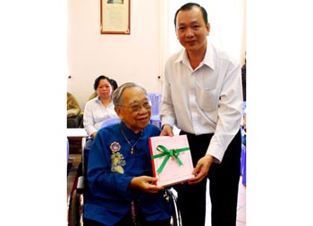 Representative of HCMC General Sciences Library hands over recognition of the Tran Van Khe Library to the professor (L) at his house.