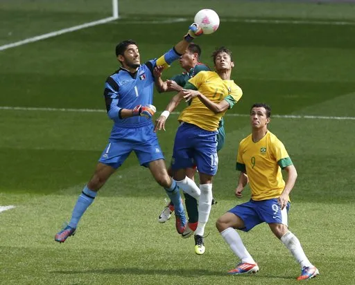 Thủ môn Corona đấm bóng trước tình huống áp sát của Neymar (số 11) và Damiao của Brazil.