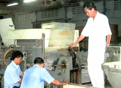 Anh Lâm Quang Trí (đứng) hướng dẫn công nhân kiểm tra hoạt động của máy in.