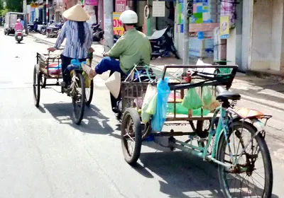Vừa chạy xe gắn máy kéo xe ba gác phía sau, vừa đẩy xe ba gác phía trước trên đường Trường Chinh, quận Tân Bình.
