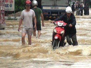 Floodwaters flow over Highway 1A in the central region (Photo: VNA)