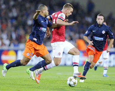 Tiền đạo Lukas Podolski (giữa, Arsenal) đi bóng trước hậu vệ Montpellier.