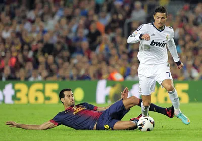 Cristiano Ronaldo (phải) vượt qua tiền vệ Sergio Busquets của Barcelona. Ảnh: AFP