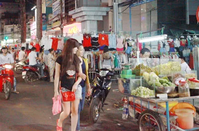 Các quầy bán quần áo di động và xe đẩy bán trái cây tràn xuống lòng lề đường.