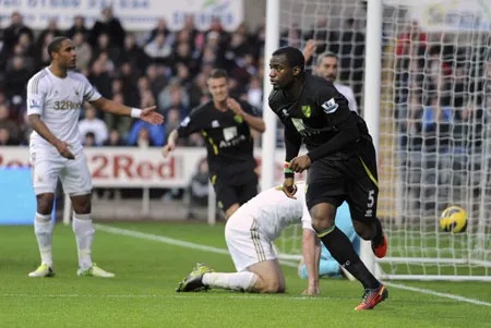 Sebastien Bassong (phải, Norwich) mừng bàn thắng vào lưới Swansea ở trận thắng 4-3 lượt đi
