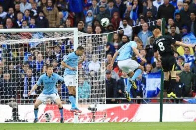 Ben Watson (số 8) trong pha bật cao đánh đầu tung lưới thủ môn Joe Hart của Man.City.