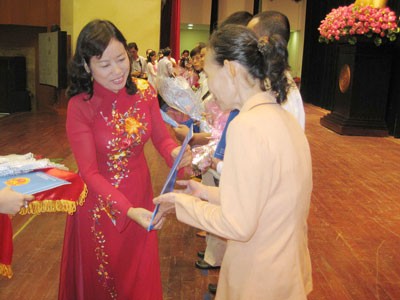 Ung Thi Xuan Huong (red dress), Director of the Justice Department in HCMC, grants citizenship papers to undocumented people (Photo: A. Chan)