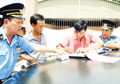 Tài xế xe có hộp đen không đạt yêu cầu, ký biên bản vi phạm. Ảnh: PHẠM KIM NGÂN