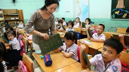 A teacher instructs a first grader how to hold a chalkboard at Nguyen Chi Thanh Primary School in District 10