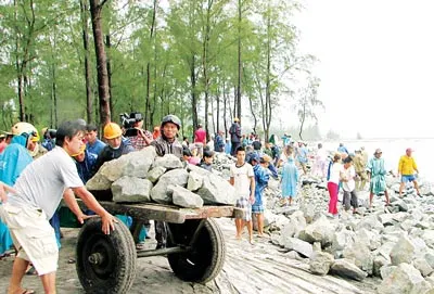 Người dân xã Hải Dương, thị xã Hương Trà, tỉnh Thừa Thiên - Huế bất chấp mưa bão số 8, khẩn cấp chèn đá hộc chống biển xâm thực vào sáng 18-9. Ảnh: Văn Thắng
