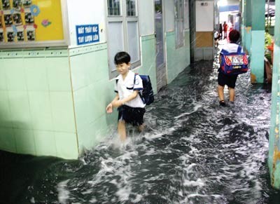 Pupils wade in the water at Hoa Binh Elementary School. (Photo: SGGP)