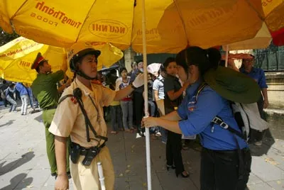 Cảnh sát giao thông cùng các tình nguyện viên dựng dù che nắng cho người dân.