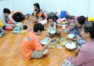 Người dân xã Long Hòa ăn tối tránh áp thấp nhiệt đới tại Trường Tiểu học Long Thạnh. Ảnh: KIM NGÂN