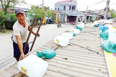 Người dân xã Hòa Nhơn, huyện Hòa Vang, TP đà Nẵng dùng can nhựa chứa đầy nước để chèn mái nhà chống bão.