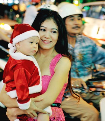 Baby is dressed up in Santa outfit on street.