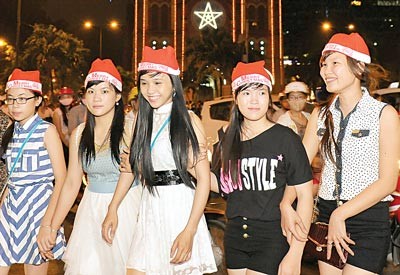 Young people enjoys Christmas in Ho Chi Minh City Baby is dressed up in Santa outfit on street. People tried to reach the Notre Dam Cathedral.