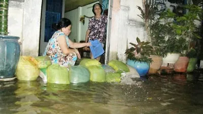 Một gia đình đang tát nước ra khỏi nhà. Ảnh: Thế Trịnh