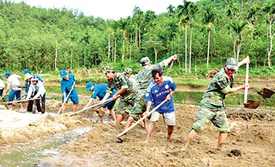 Chiến sĩ cùng người dân xã Ba Xa (Ba Tơ, Quảng Ngãi) khắc phục sa bồi do lũ vào tháng 11-2013.