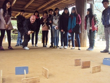 Young visitors see a foreigner playing a Vietnamese folk game at the Museum of Ethnology.